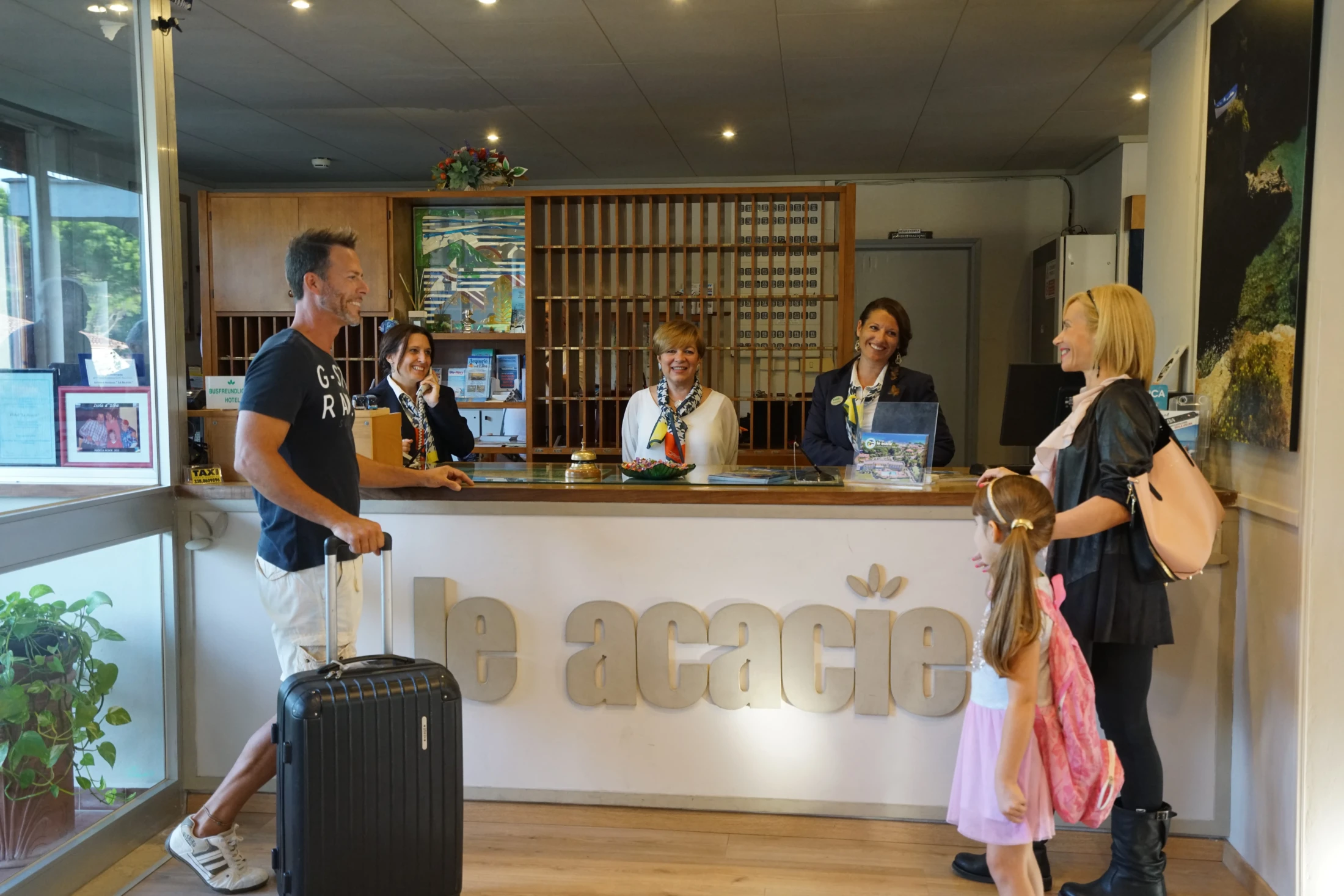 Reception dell'Hotel Le Acacie con staff e ospiti, famiglia con bambina in check-in
