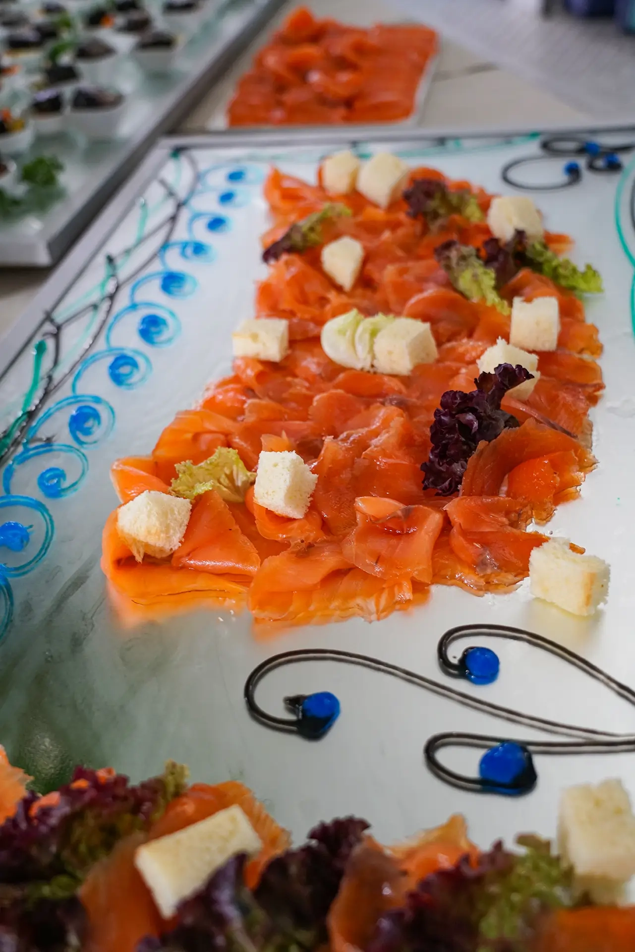 Carpaccio di salmone con cubetti di formaggio su piatto in ceramica decorato, buffet dell'hotel all'Elba