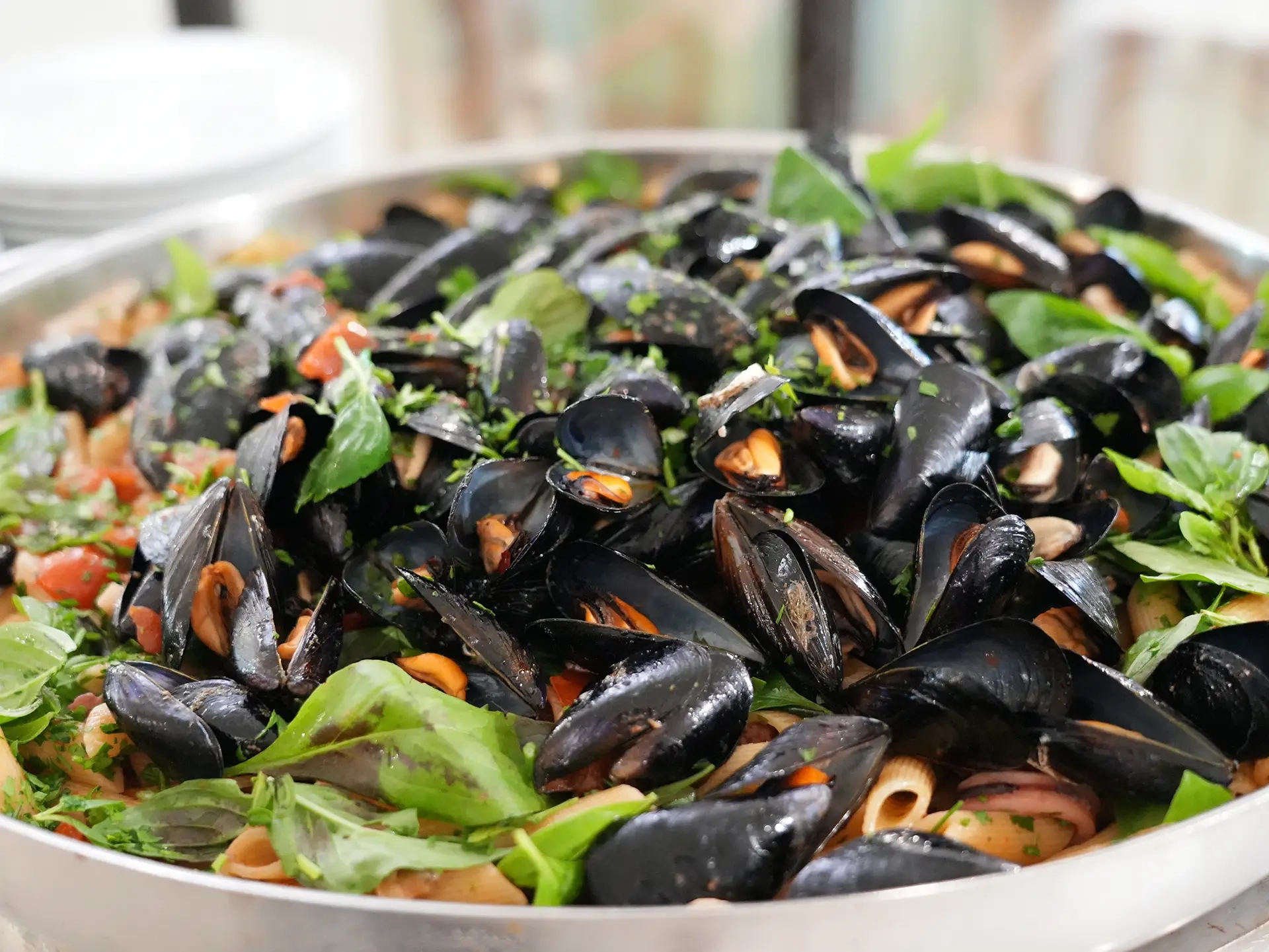 Cozze fresche con pasta e basilico servite in un grande vassoio per il buffet dell'hotel