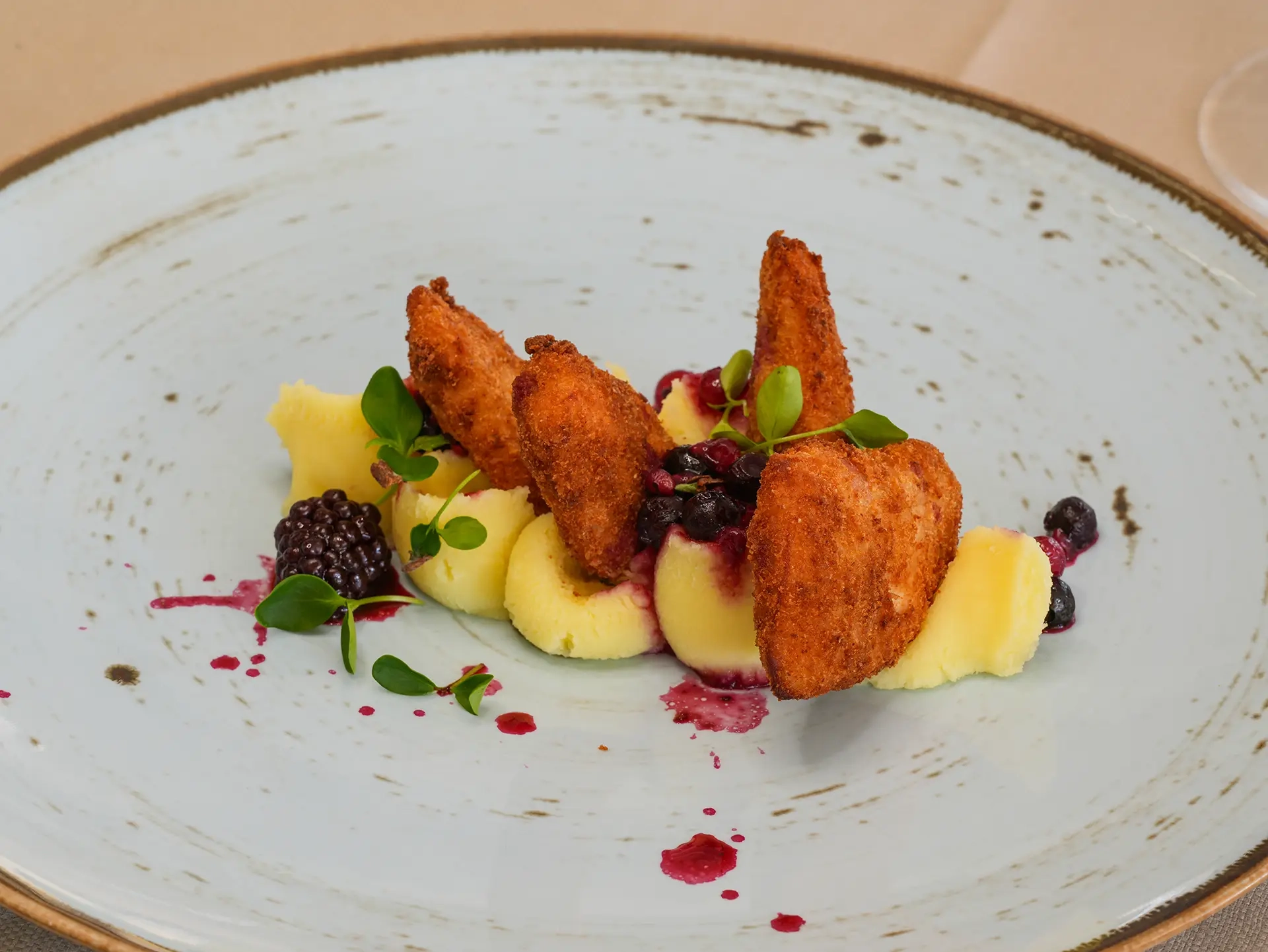 Piatto gourmet con gamberi croccanti, purè di patate e salsa ai frutti di bosco