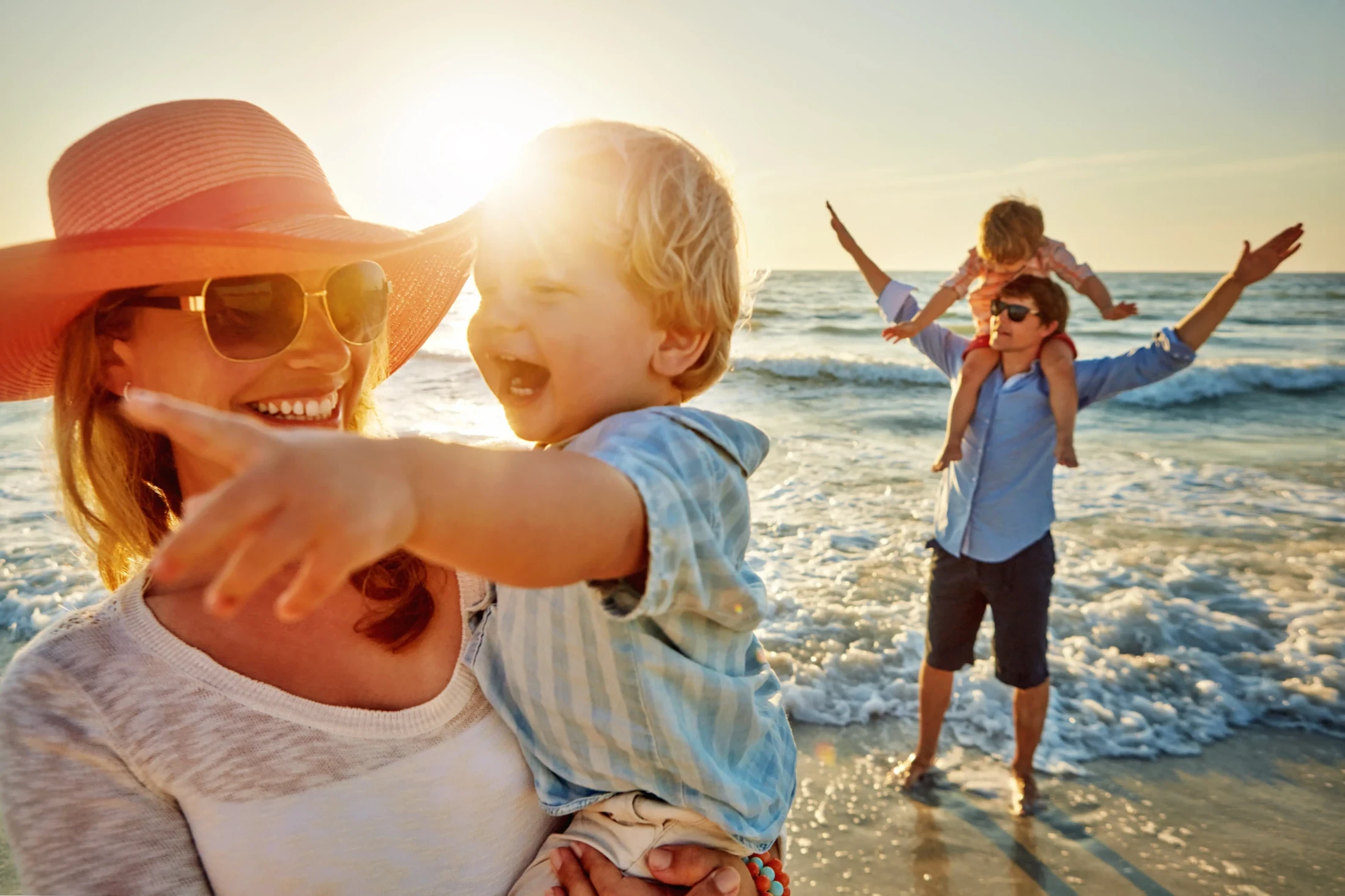 Famiglia gioca sulla spiaggia dell'Elba al tramonto, bambini felici in braccio ai genitori