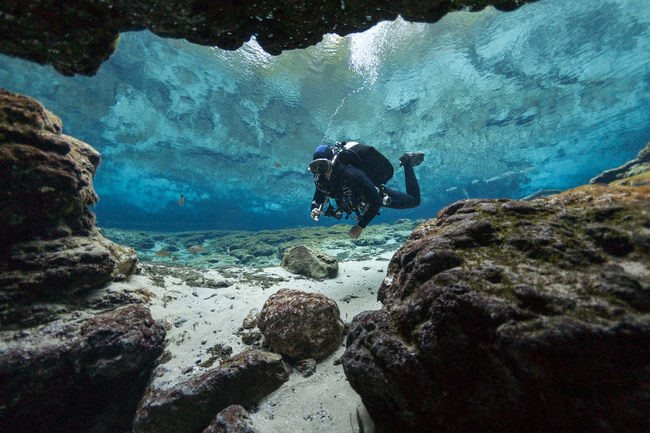 Taucher schwebt in einer Felsenhöhle im türkisblauen Wasser vor Elba