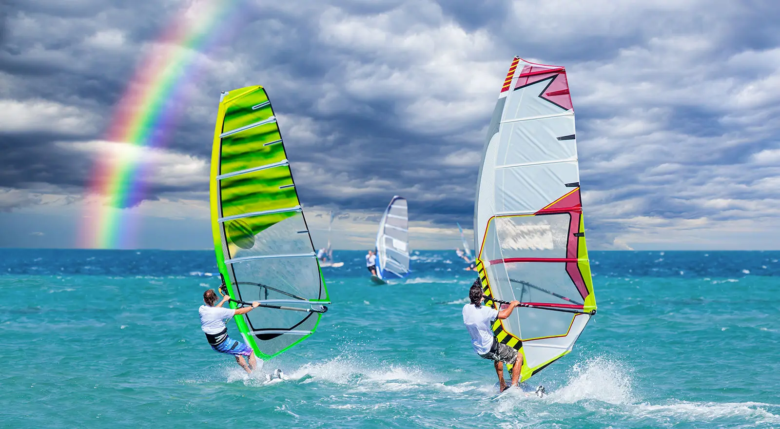 Windsurfisti in azione sul mare dell'Elba con arcobaleno sullo sfondo