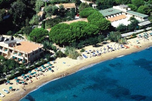 Spiaggia con ombrelloni e edifici circondata da vegetazione vista dall'alto.